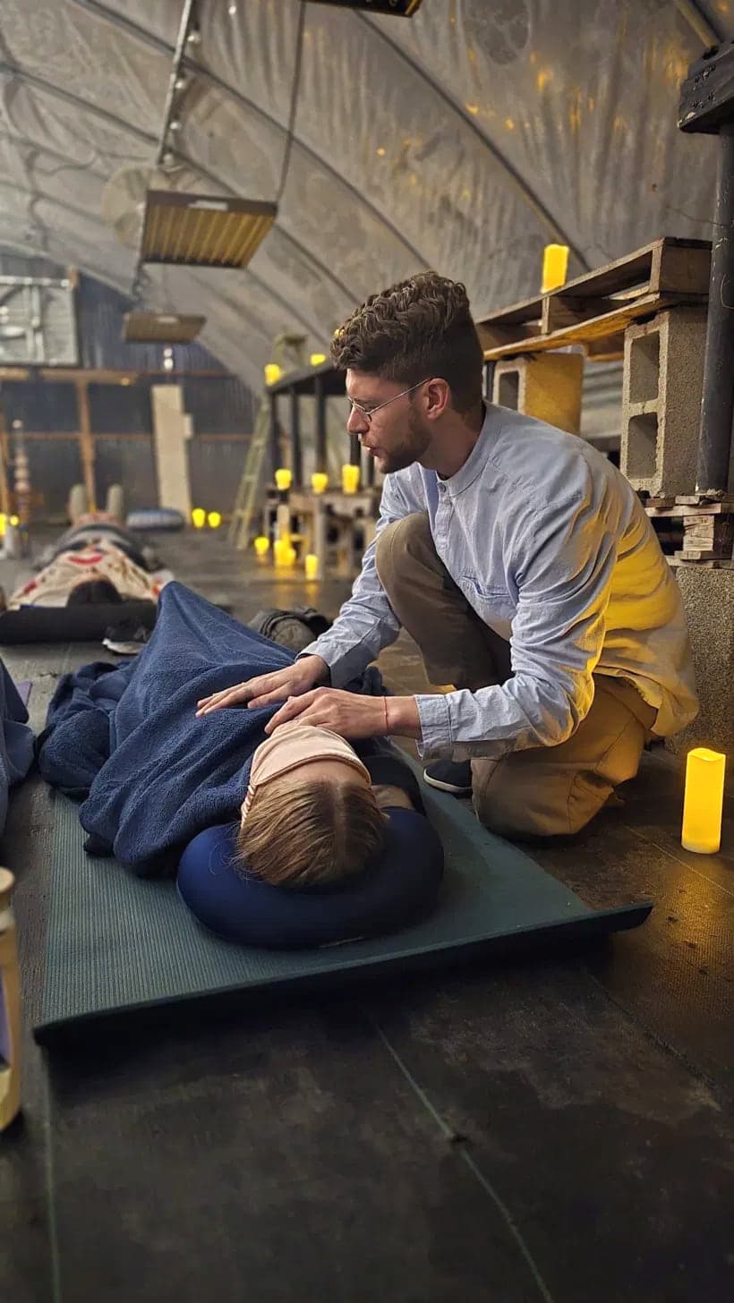 David offering hands-on spinal attunement, his hands resting with presence on a person lying still